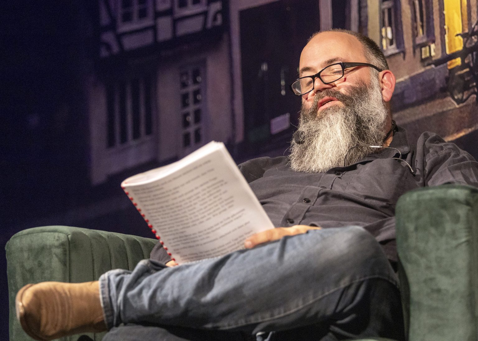 Micha Krämer wie er sitzend aus einem Manuskript liest