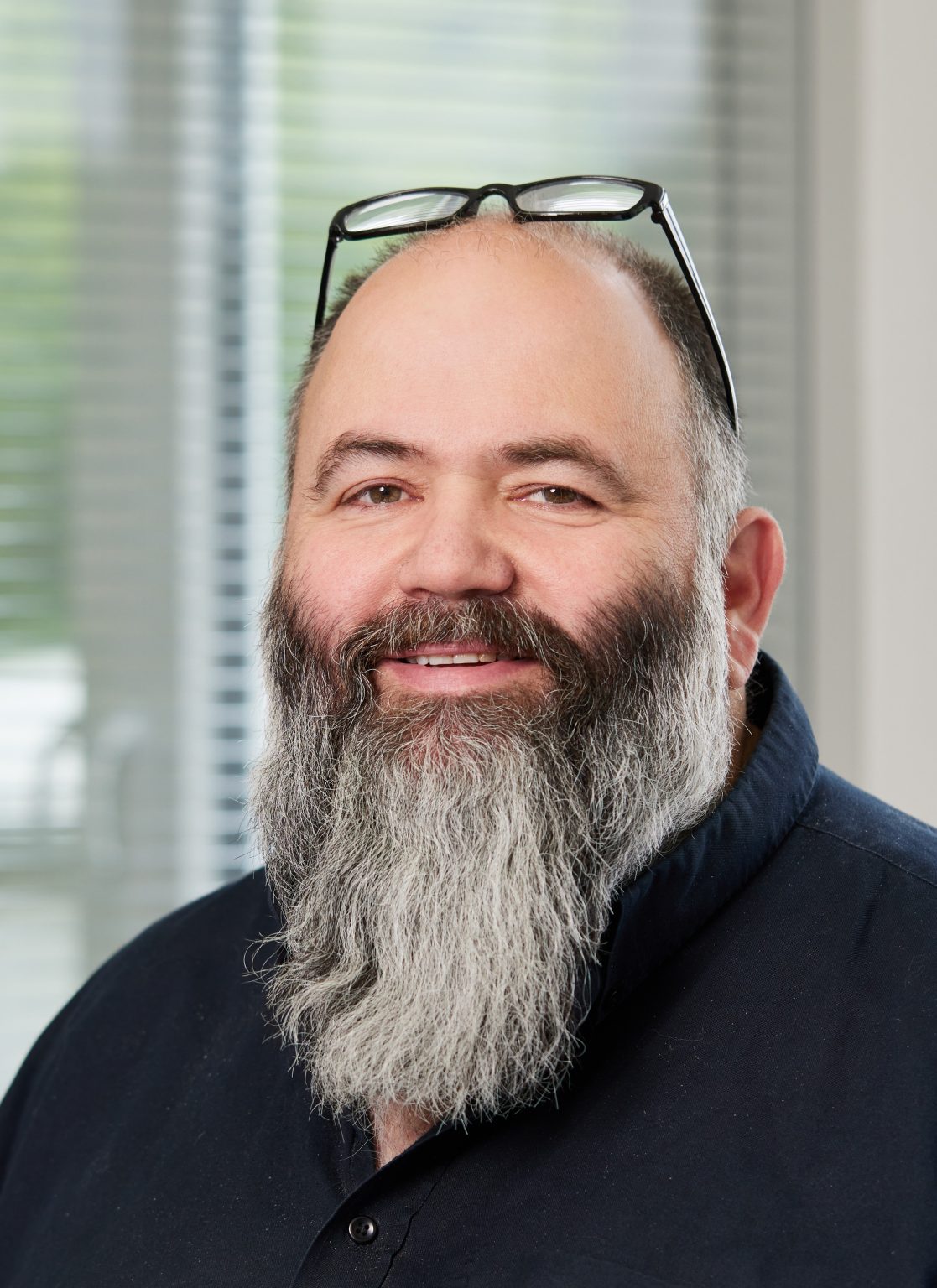 Micha Krämer lächelt in die Kamera mit Brille auf dem Kopf und schwarzem Hemd