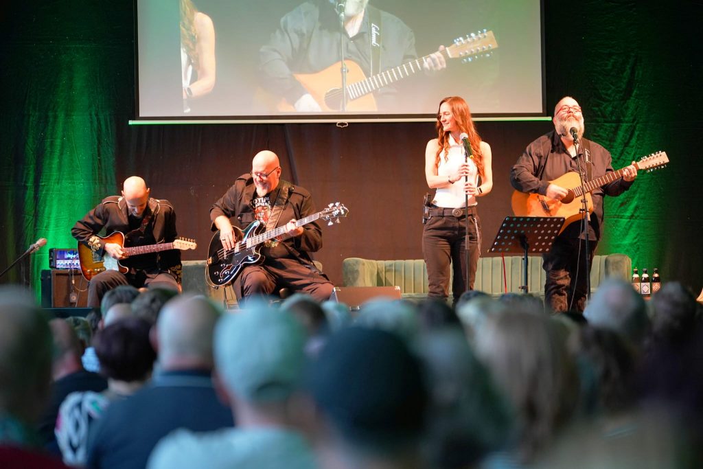 Foto von Arne, Thilo, Lorena und Micha Krämer auf einer Bühne mit Zuschauern im Vordergrund